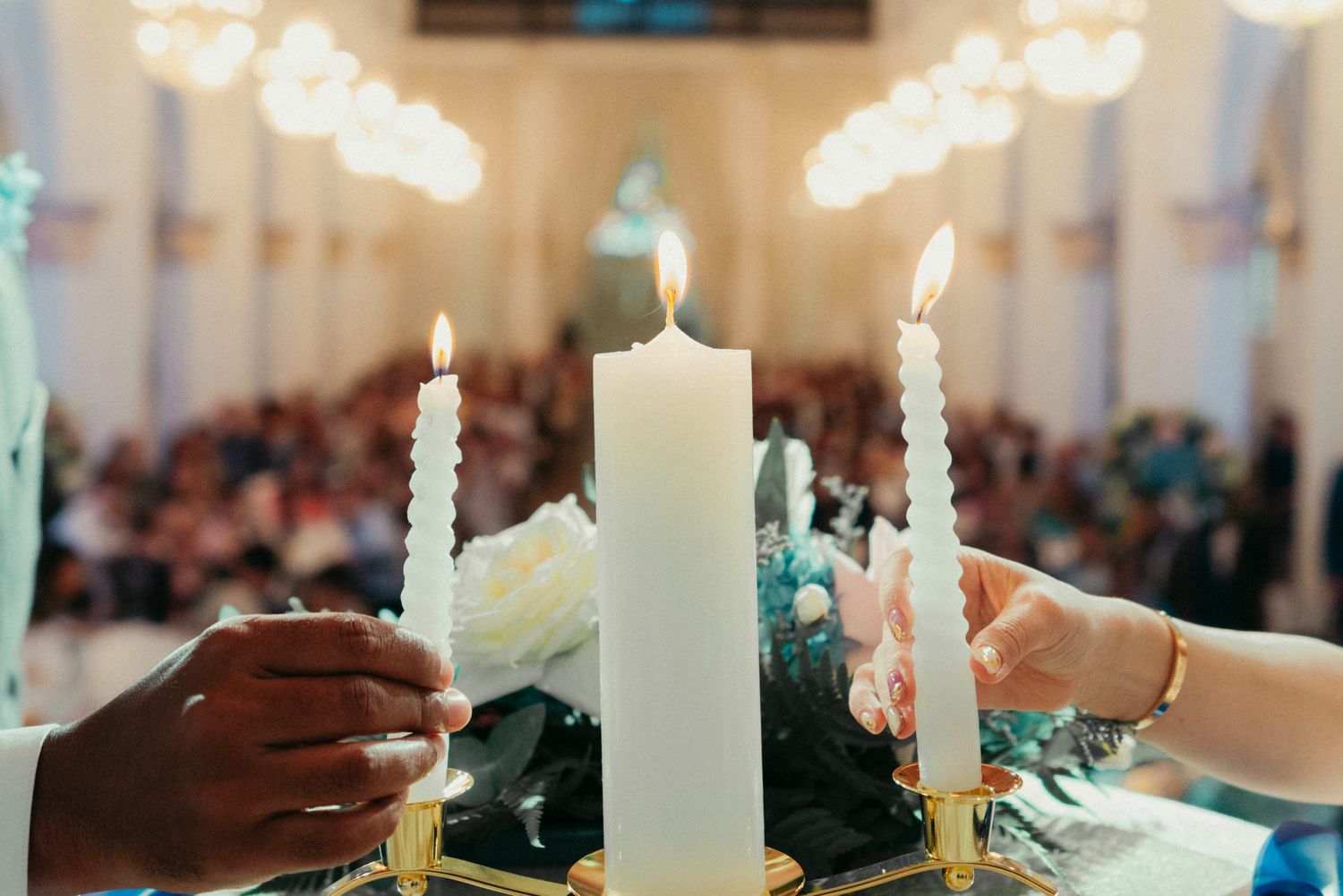 Unity candle ceremony at a church wedding with guests seated in background.