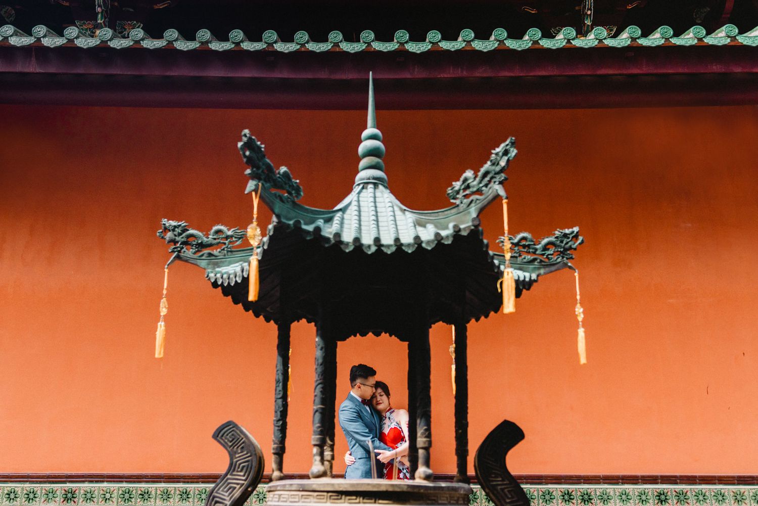 Traditional Chinese pavilion roofline with ornate details against orange wall.
