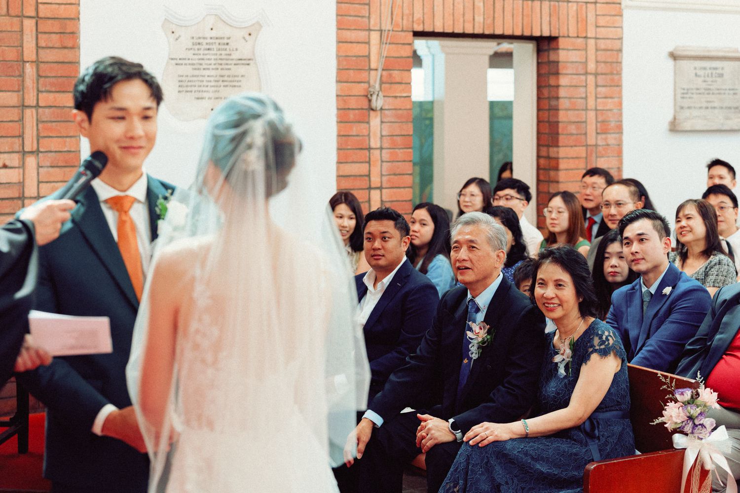 Wedding ceremony in progress at traditional brick church with guests seated in pews.