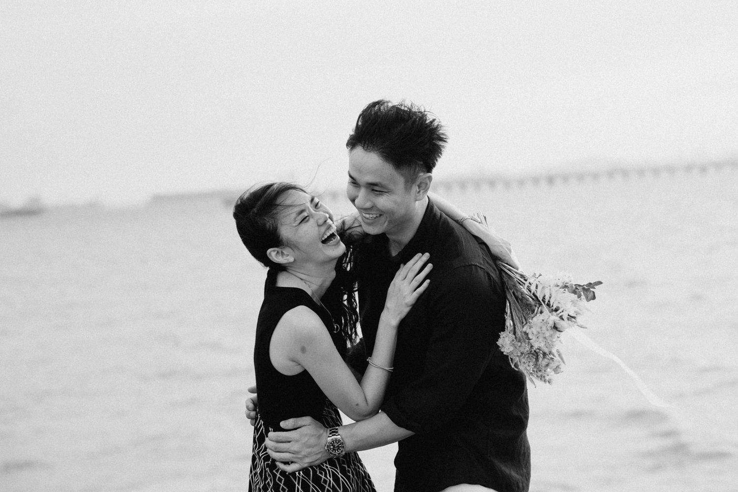Romantic couple shares intimate moments in black and white photos at the beach.