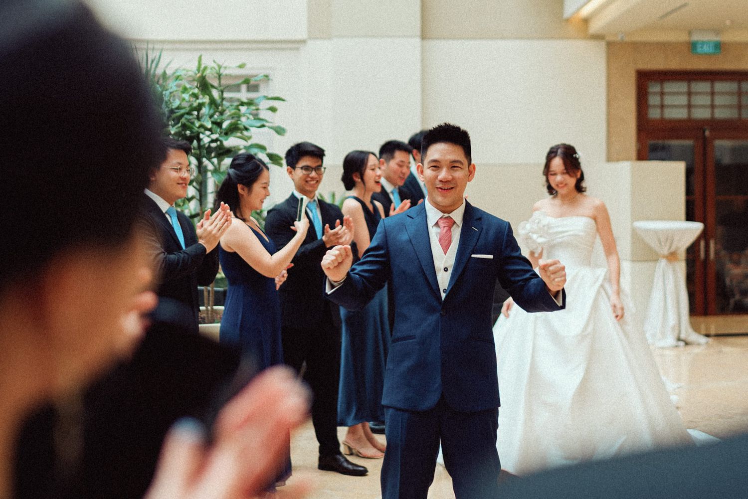 Wedding party celebrates joyfully during outdoor ceremony with guests clapping and smiling.