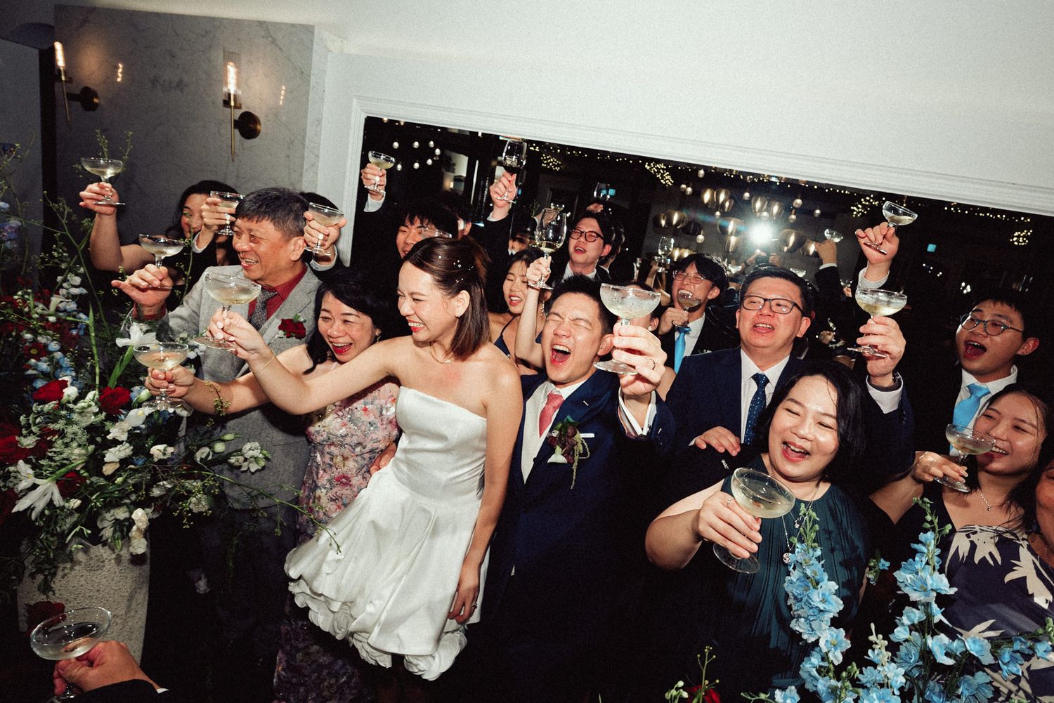 A group of wedding guests dancing and celebrating together on the dance floor at a reception party.