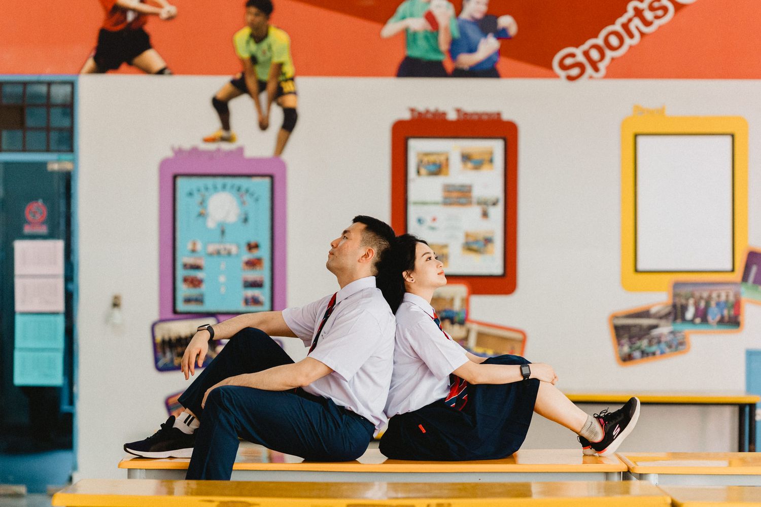 Students engaged in various activities in a bright school hallway with sports signage.