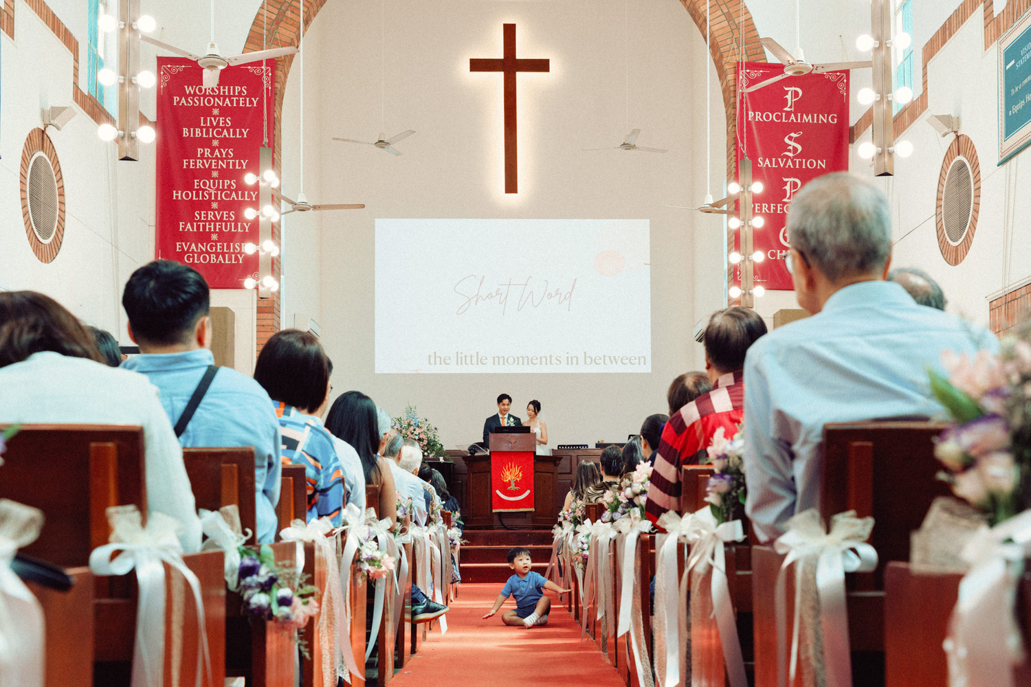Interior of a church during a service with red decor and traditional religious elements.