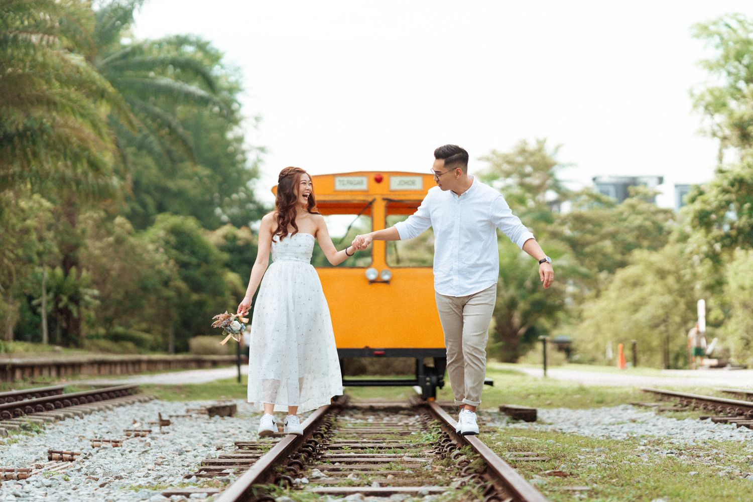 Scenic railway track with an orange railcar and trees in the background.