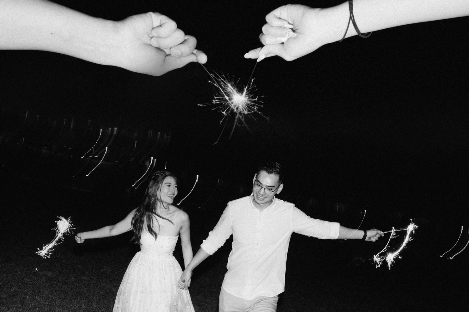Black and white photo of people holding sparklers during a nighttime celebration.