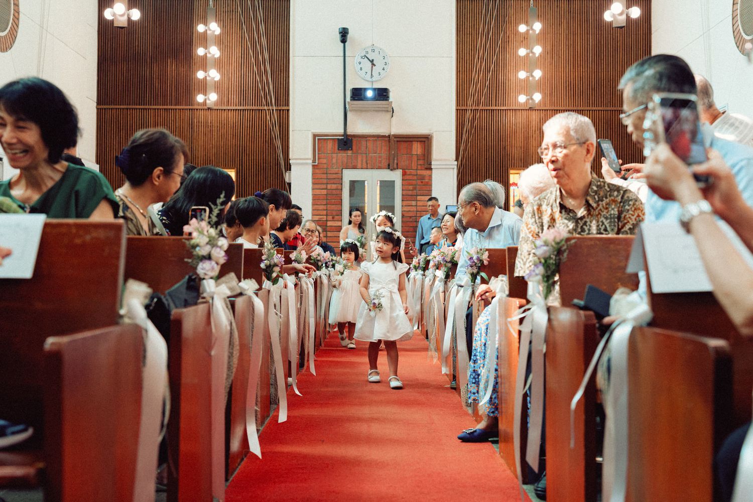 Church interior with red carpet aisle and wooden pews filled with wedding attendees.