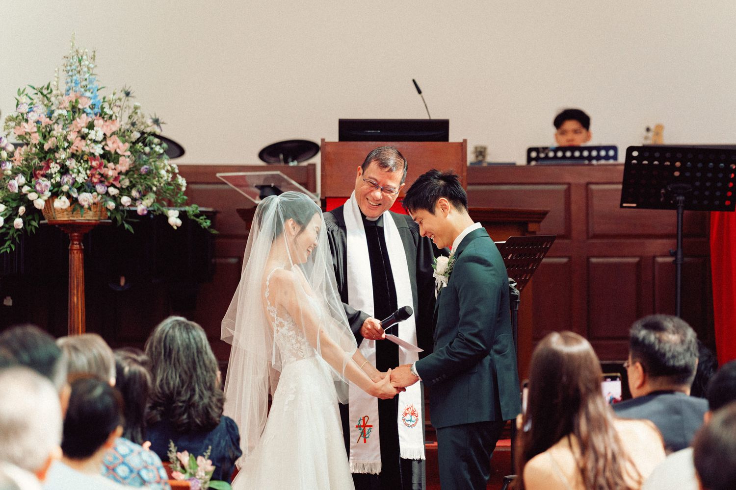 Couple exchanging vows during a traditional church wedding ceremony with guests looking on.