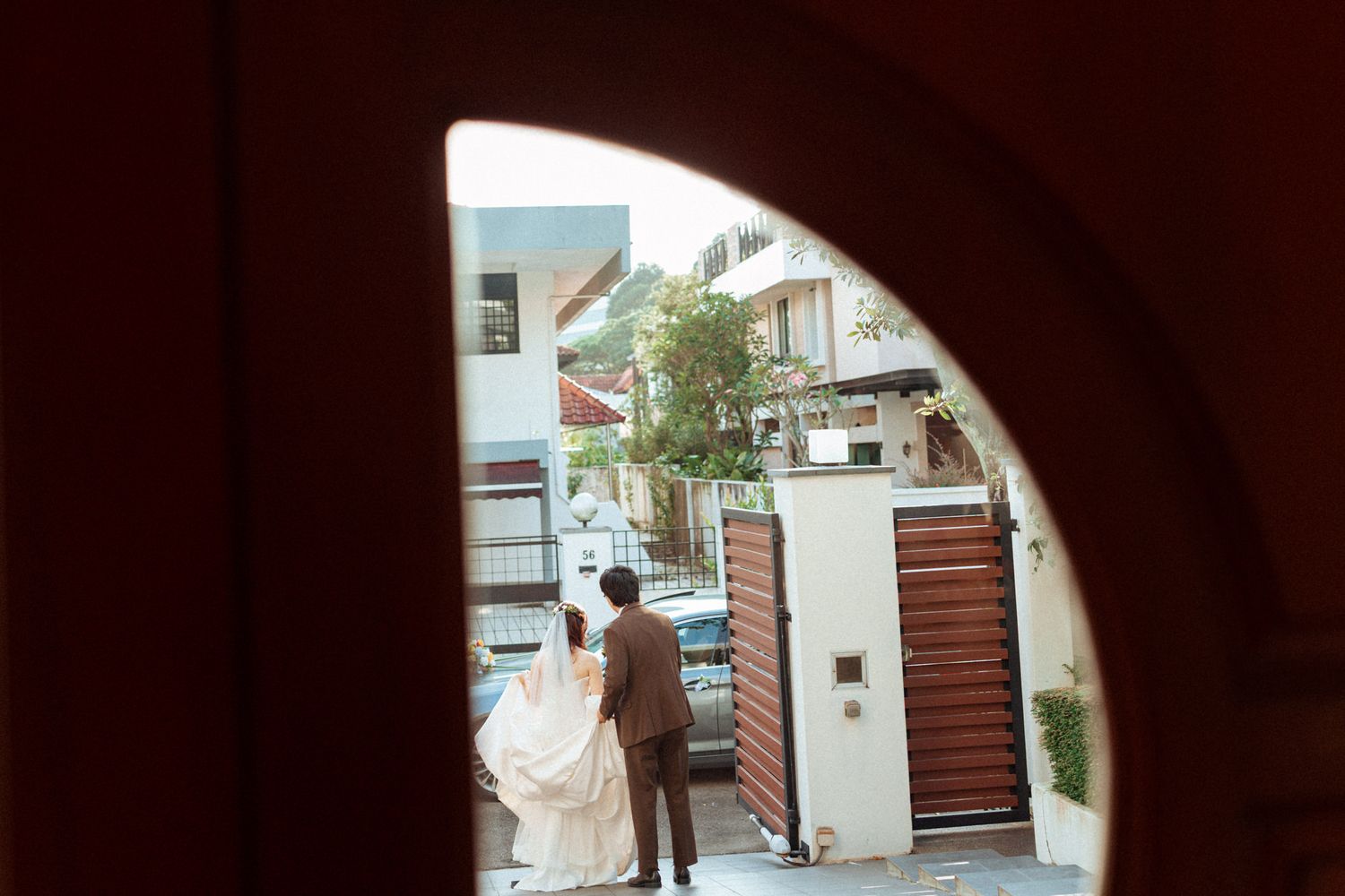 Bride and groom photographed through an arched doorway outside a building on their wedding day.