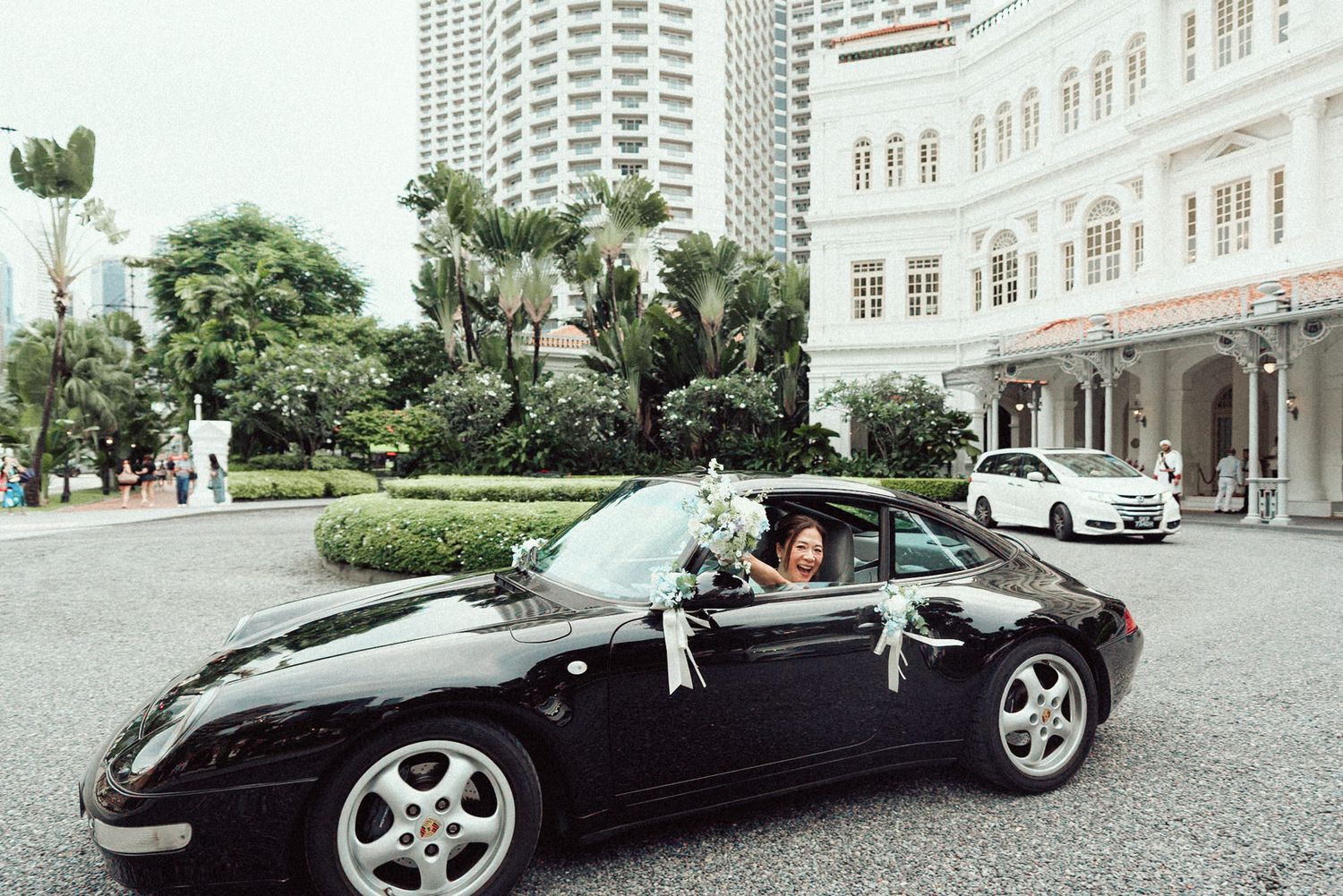 A black convertible luxury car parked in front of a white colonial style building.