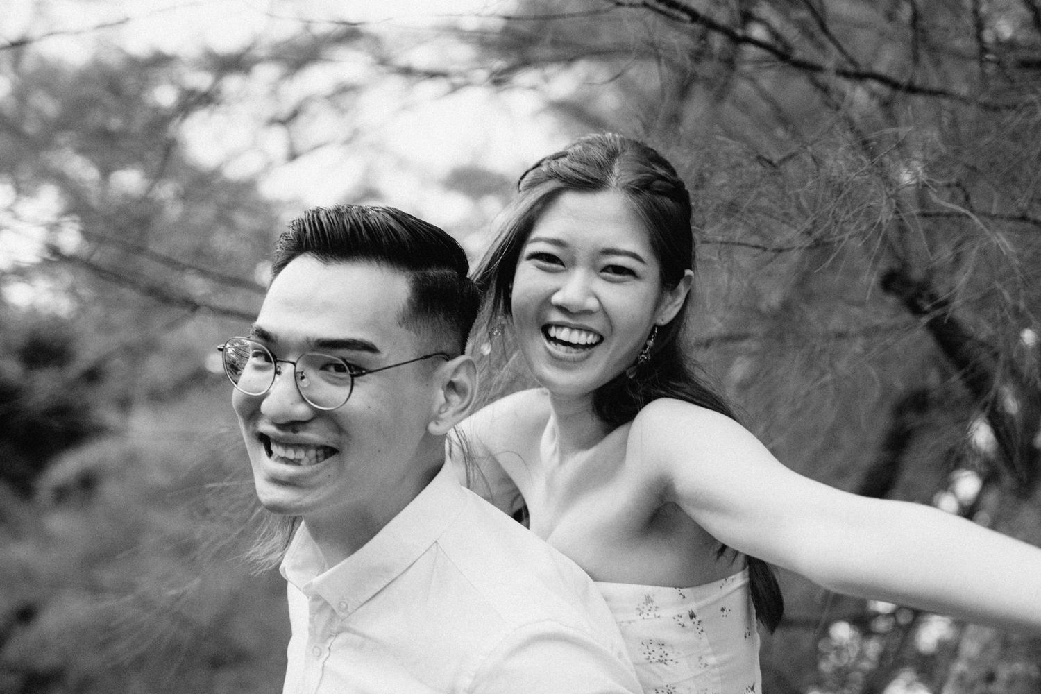 Black and white portrait of a joyful couple laughing together outdoors.