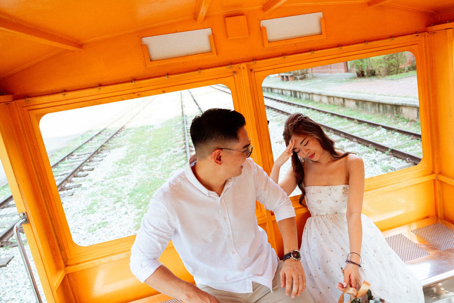 Interior view of a bright orange rail car with sunlight streaming through windows.