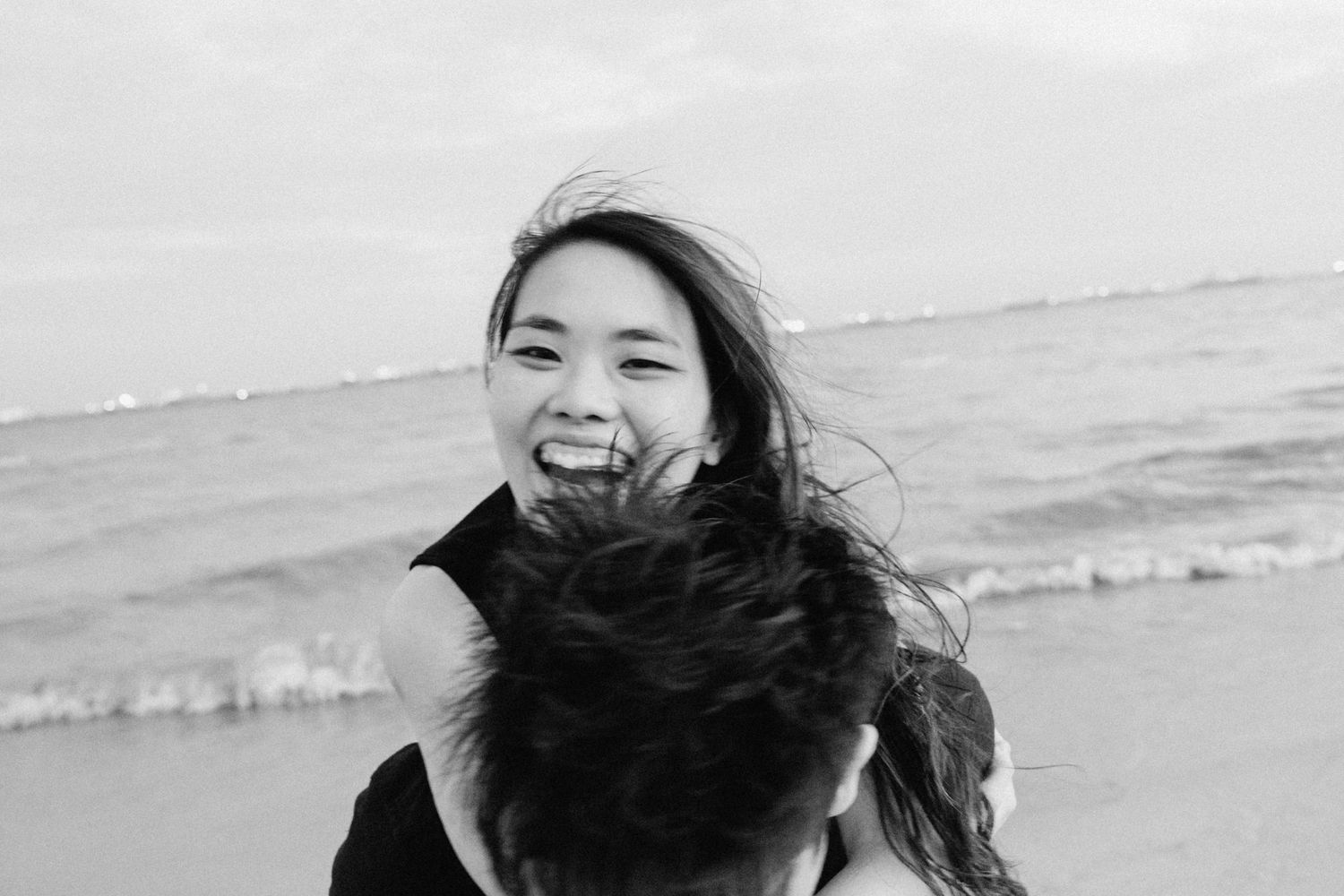 Candid moments of laughter and joy captured during a beach photoshoot.