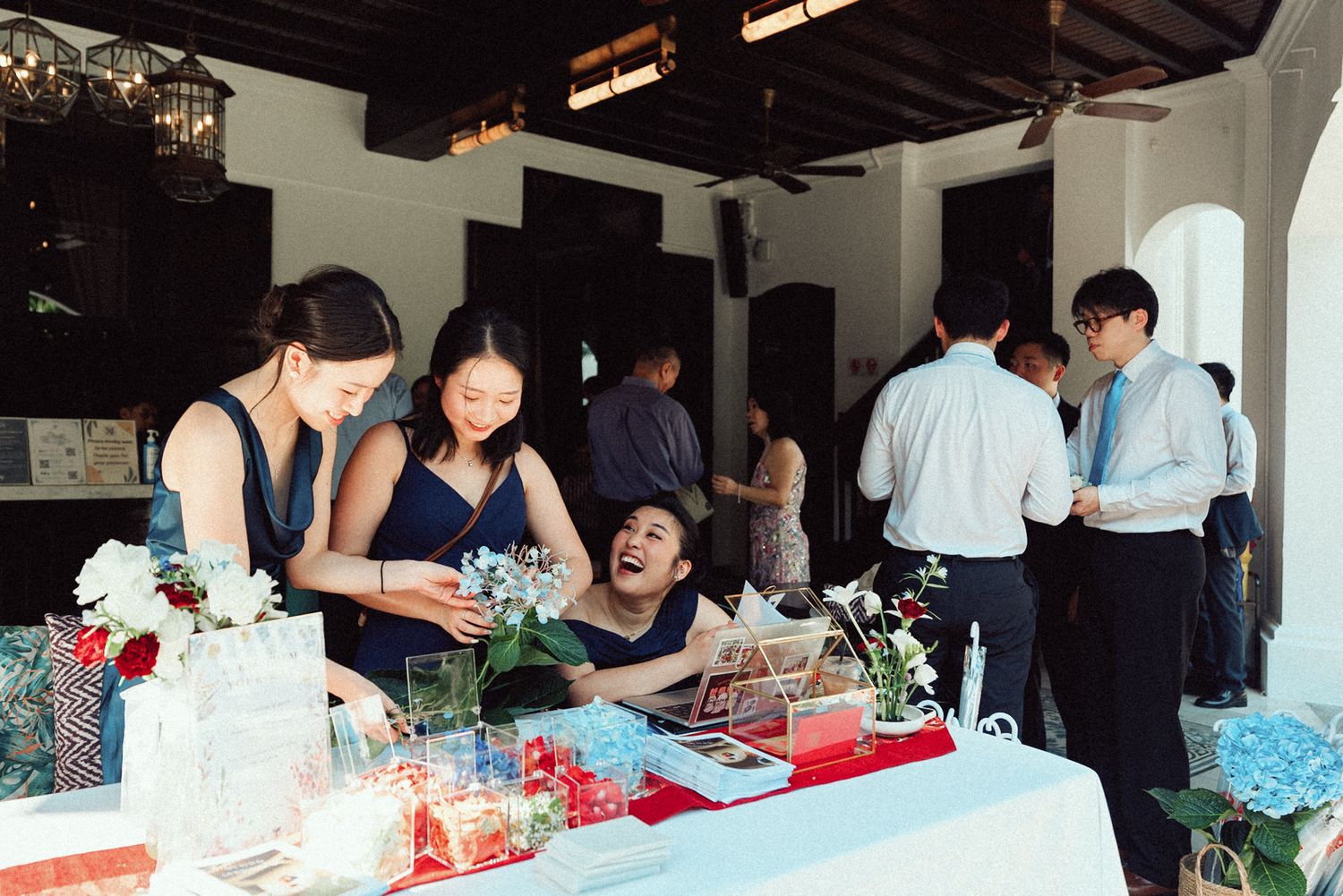 People gather around tables at a workshop making floral arrangements and bouquets in a bright indoor space.