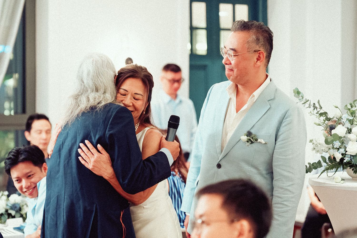 Guests at a wedding reception share joyful moments and laughter during dinner at an elegant venue.