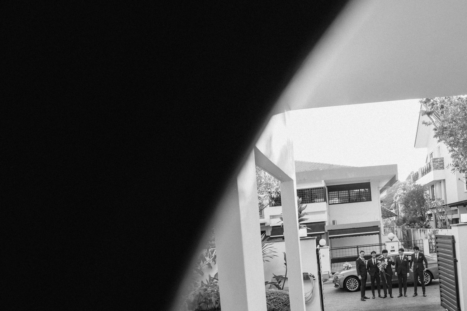 Black and white photo of a group of people standing outside a modern building, viewed through a geometric frame.