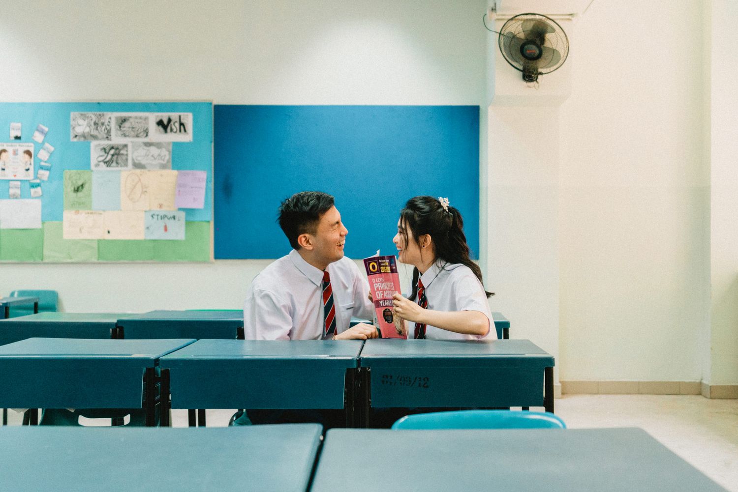 Students studying in a modern classroom with blue walls and educational posters.
