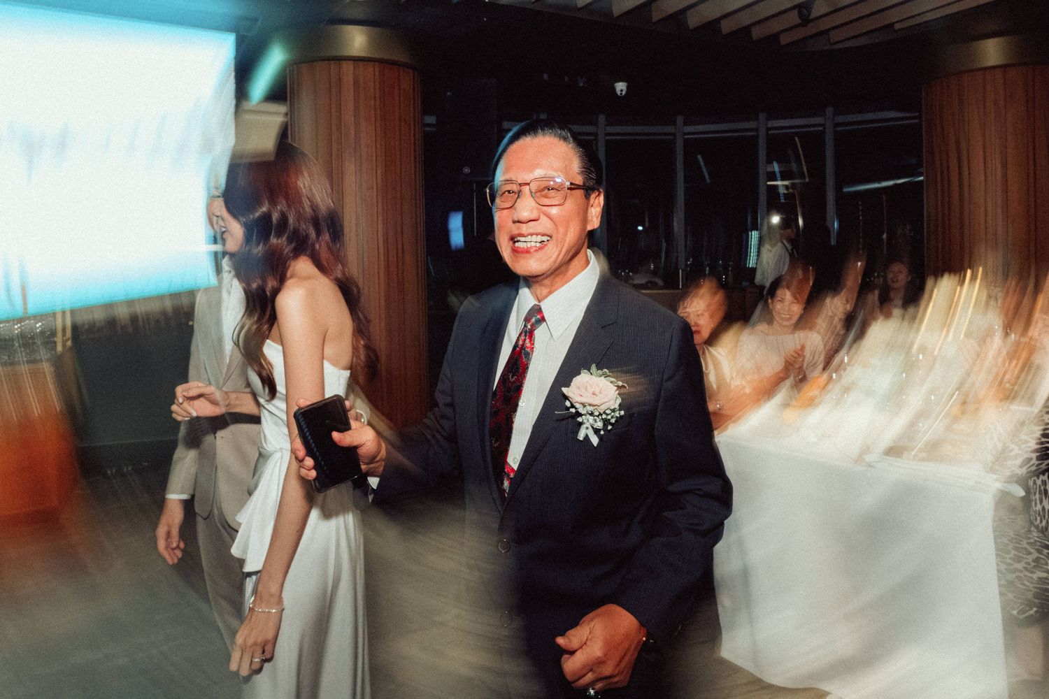 Guest enjoying themselves at an elegant wedding reception with projection screen in background.