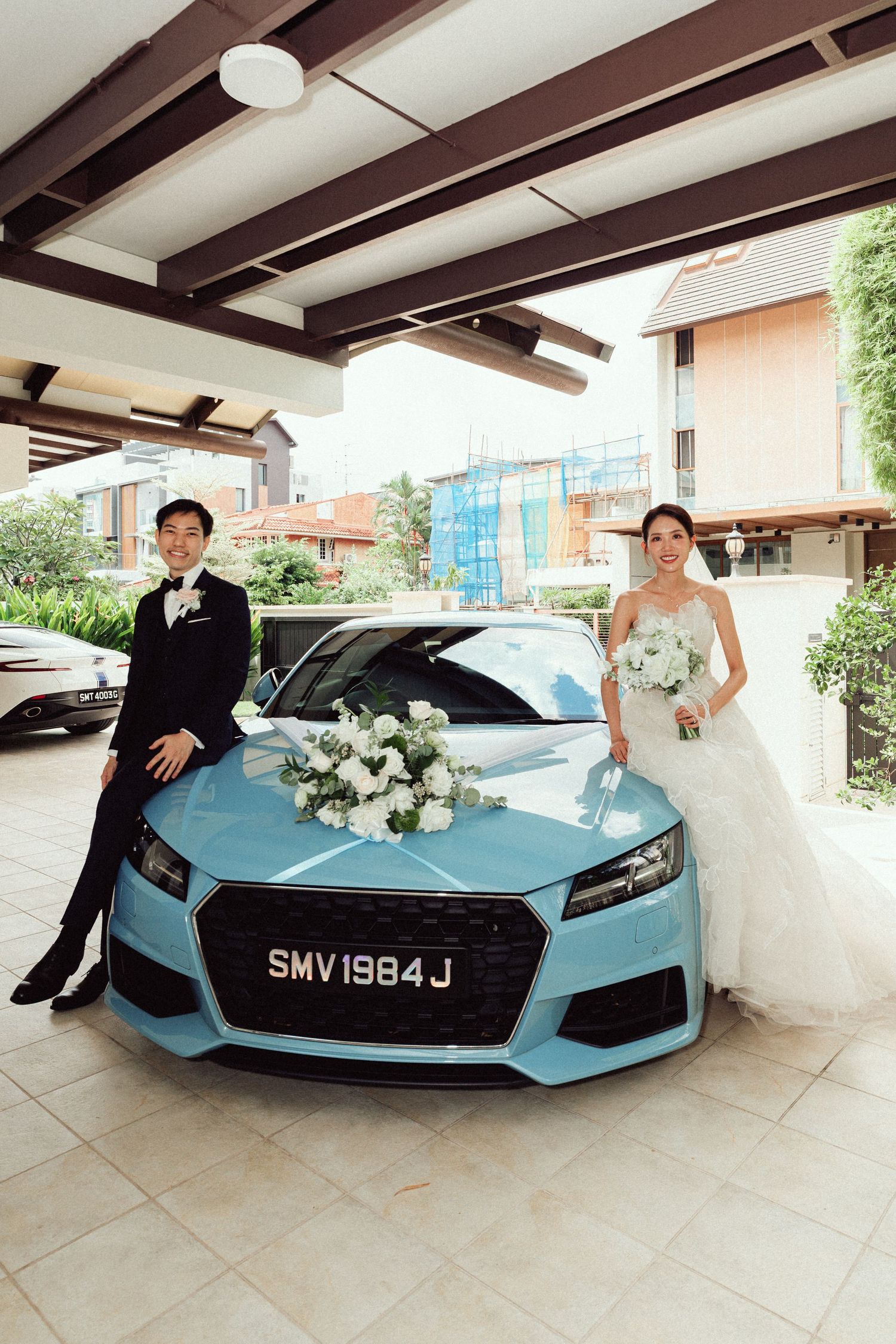 Light blue luxury sports car decorated with white flowers for a wedding.