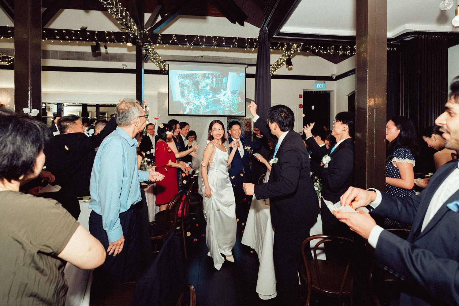Crowd of people gathered at an indoor event space with decorative lighting and architectural details.