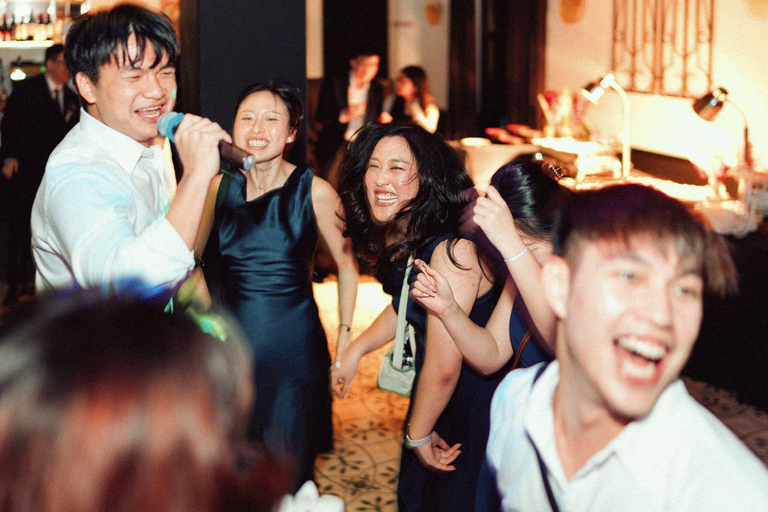 A lively group of party guests dancing and laughing together at a festive indoor celebration.