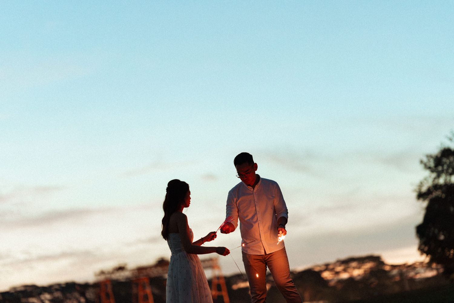 Silhouettes of a couple dancing at sunset with sparklers creating a romantic atmosphere.