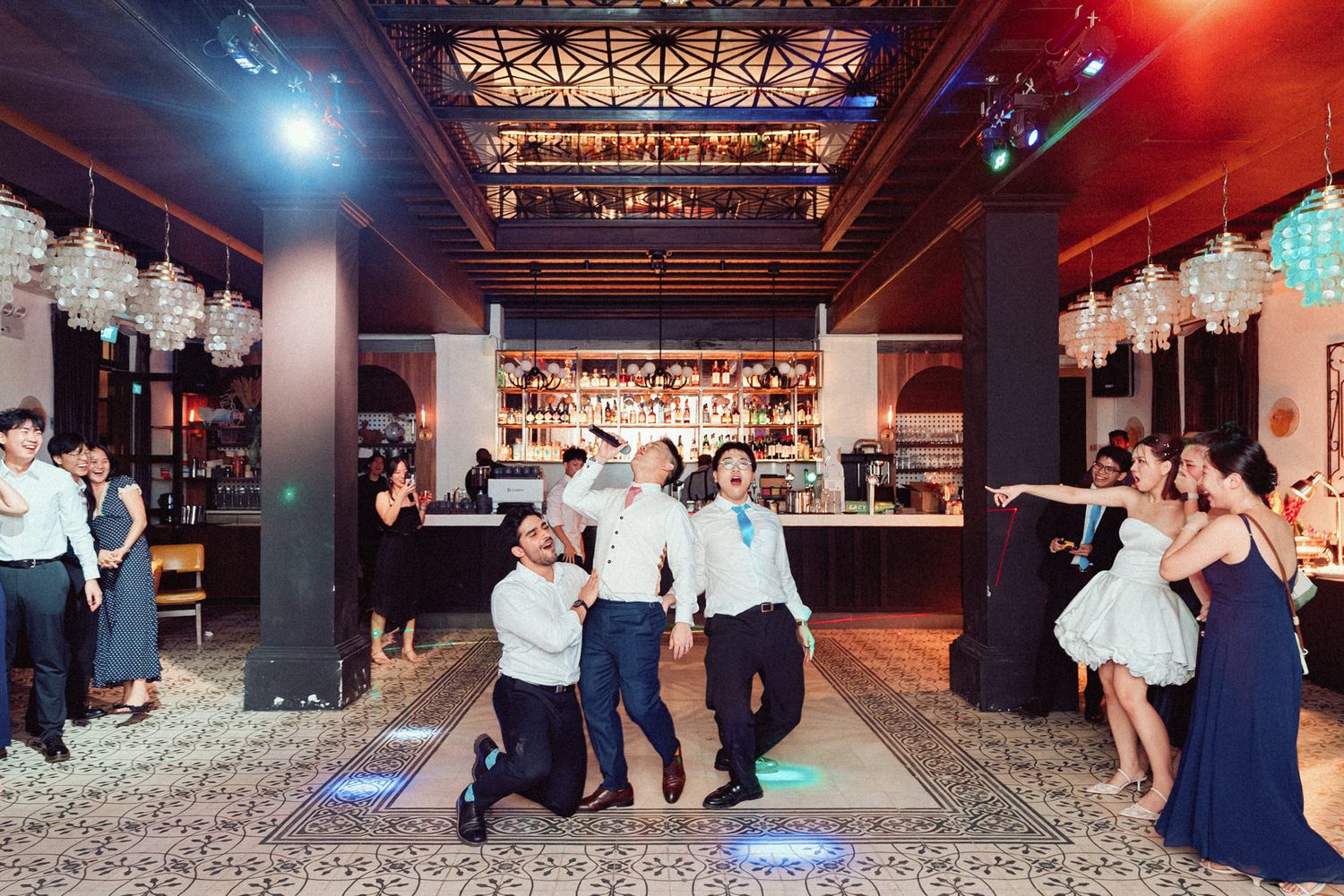 Wide view of an elegant event venue with industrial ceiling beams and ambient lighting.