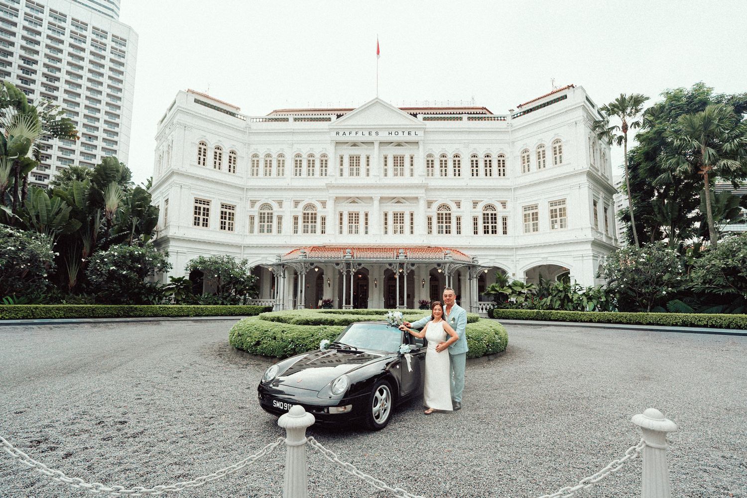 Panoramic view of a luxury hotel exterior with white colonial architecture and a classic car parked in front.