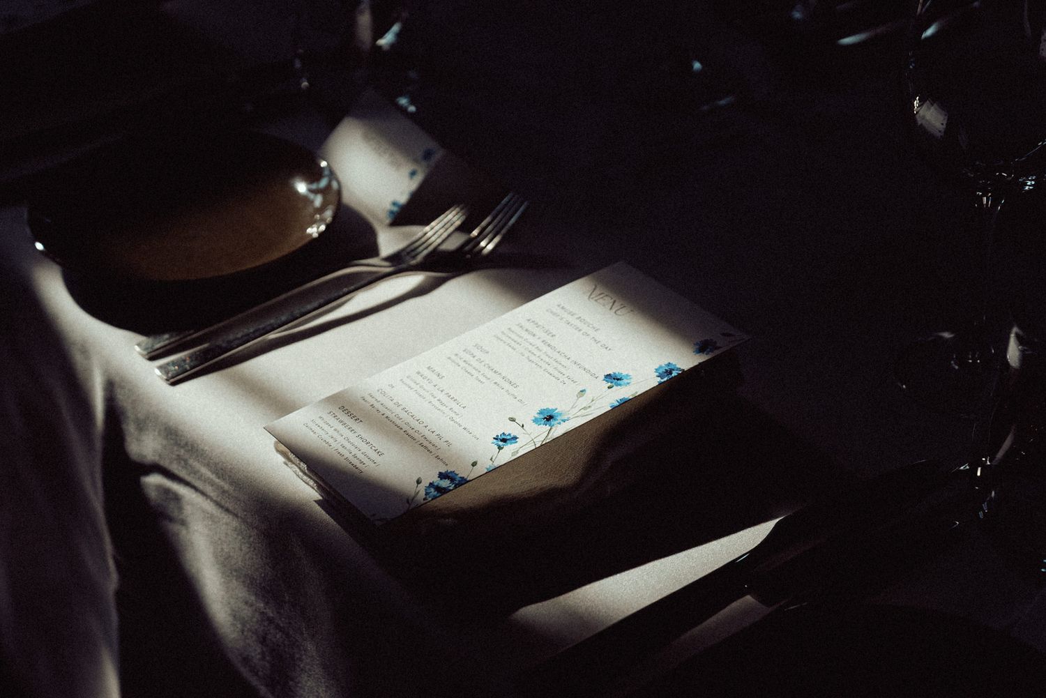 Student writing in notebook at desk with bright sunlight streaming through window creating dramatic lighting effect.