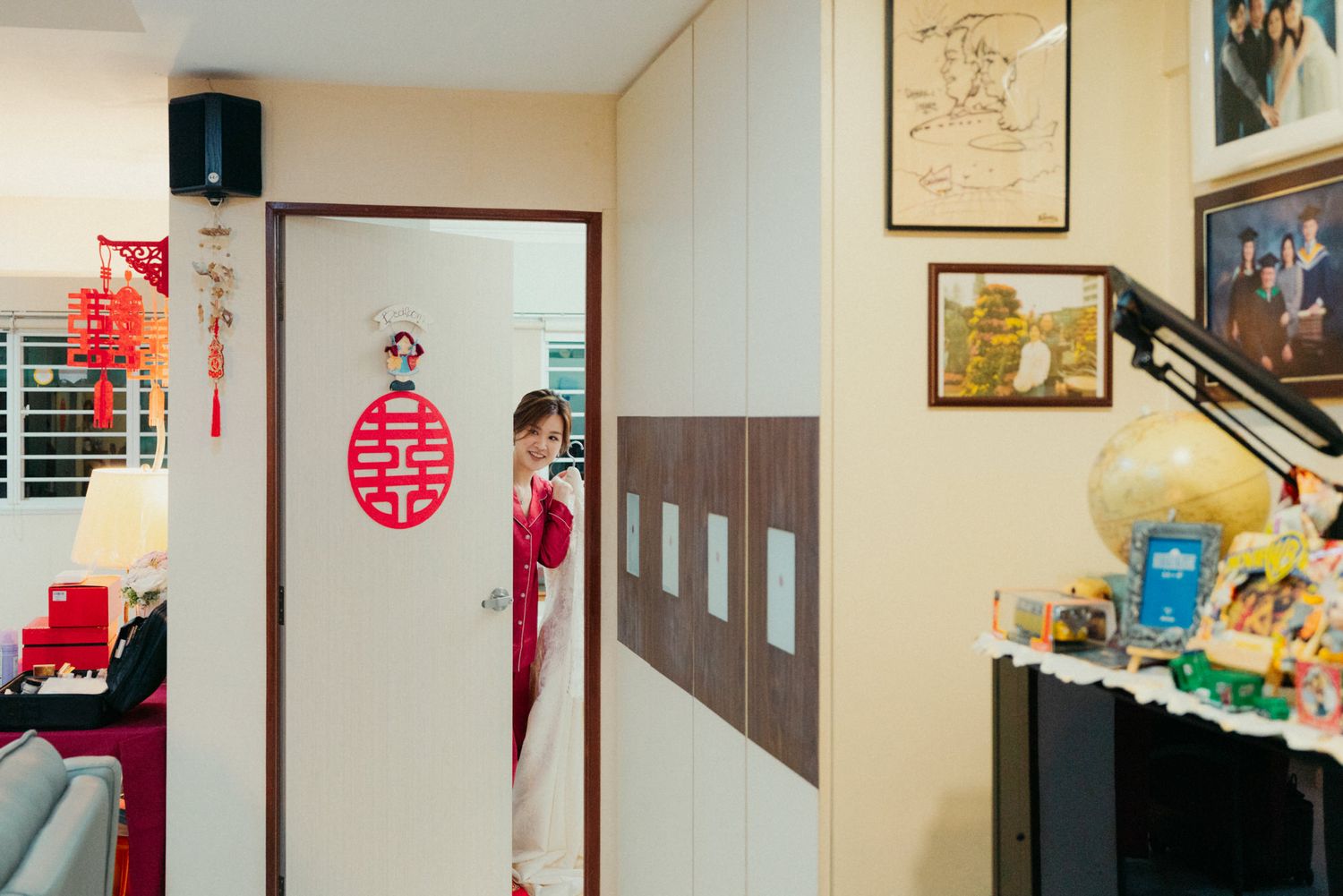 Woman in traditional red Vietnamese ao dai dress standing by a door decorated with a double happiness symbol.