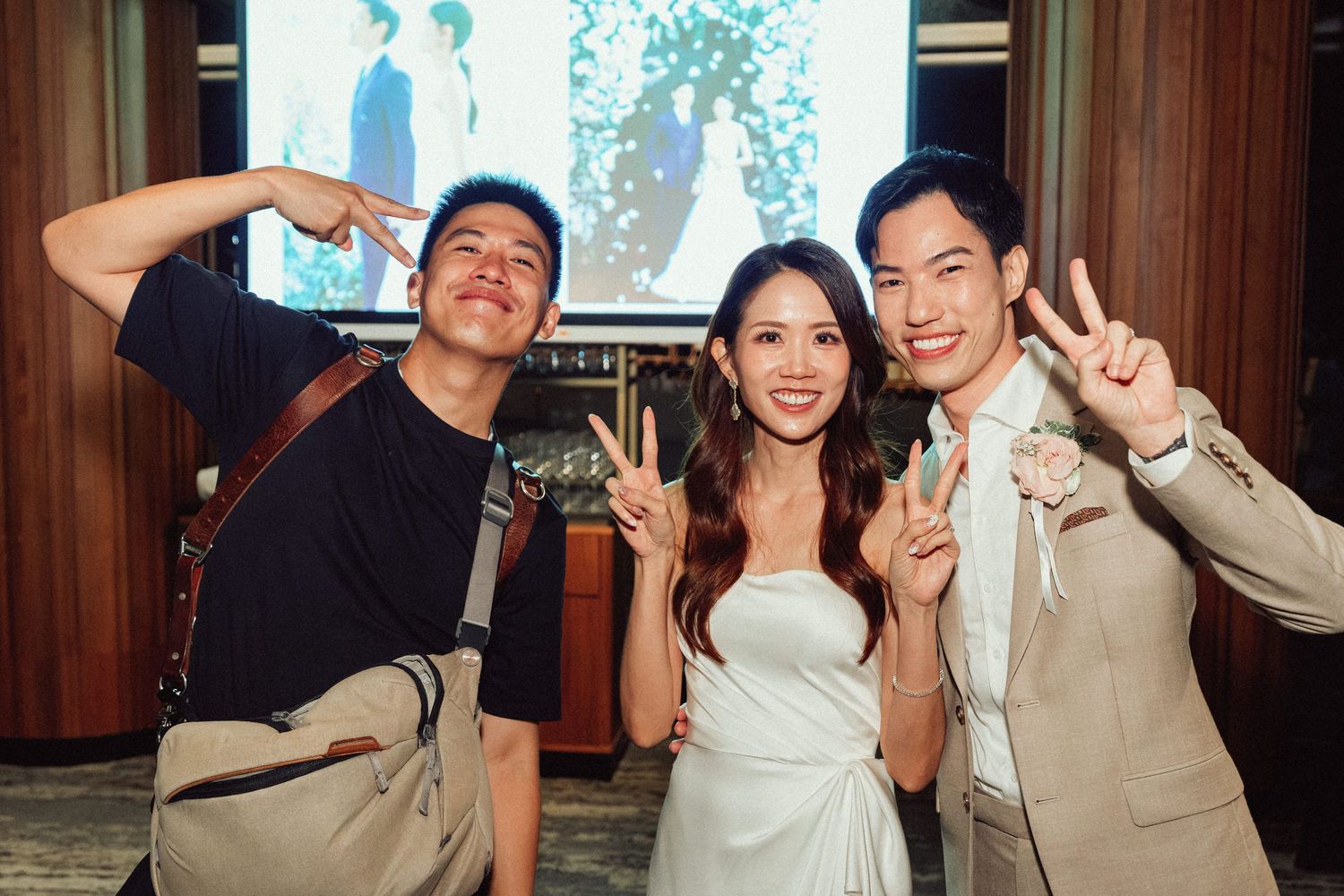 Wedding celebration with guests posing and making peace signs at reception.