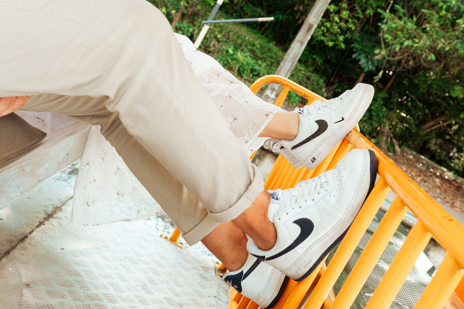 Close-up of casual footwear on railway tracks next to an orange rail car.