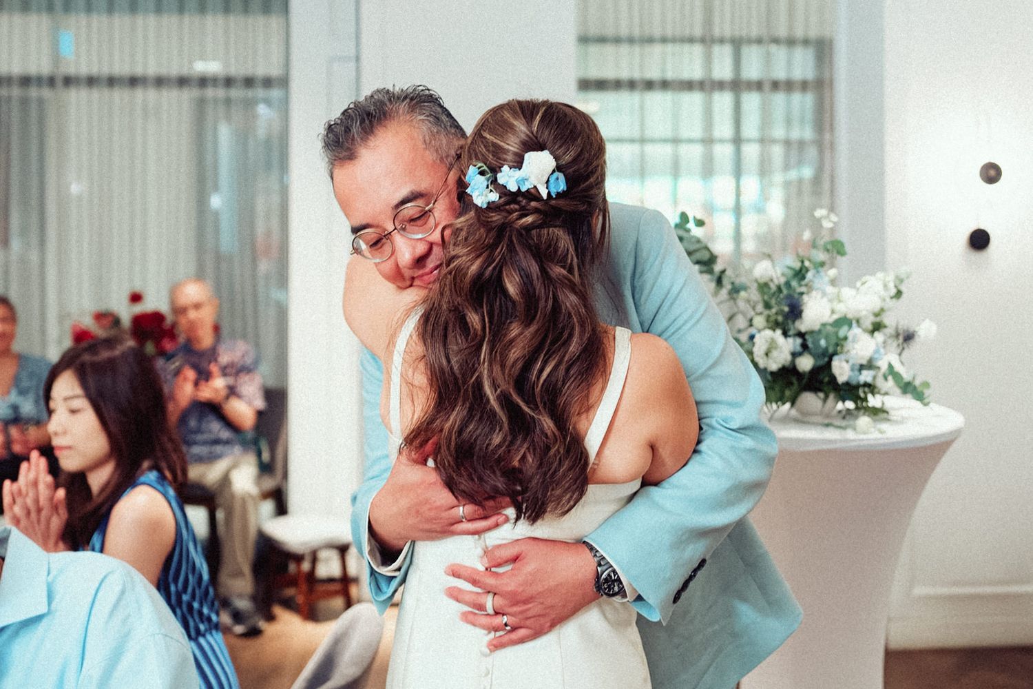 A romantic first dance moment between newlyweds in a bright, modern reception venue with floor-to-ceiling windows.