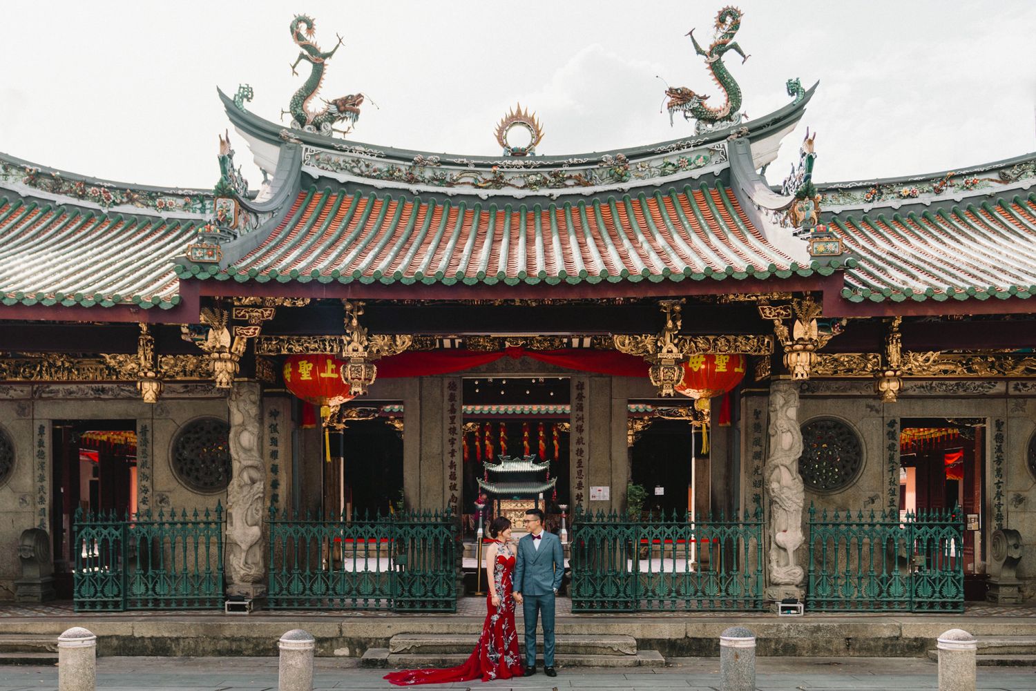 Traditional Chinese temple architecture with ornate roofs and red pillars in a row.