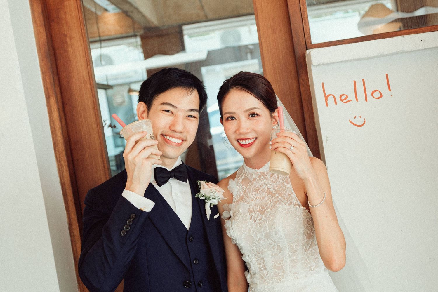 Wedding couple sharing intimate moments in front of a cafe with hello signage.