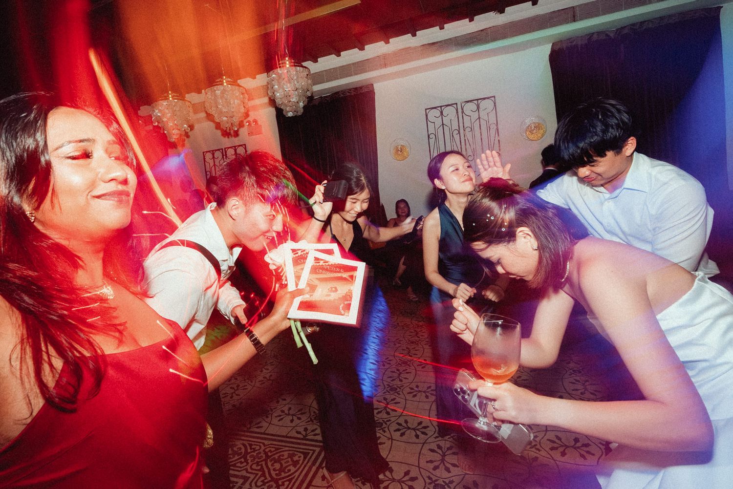 People dancing and socializing at a nightclub with red and blue lighting effects.