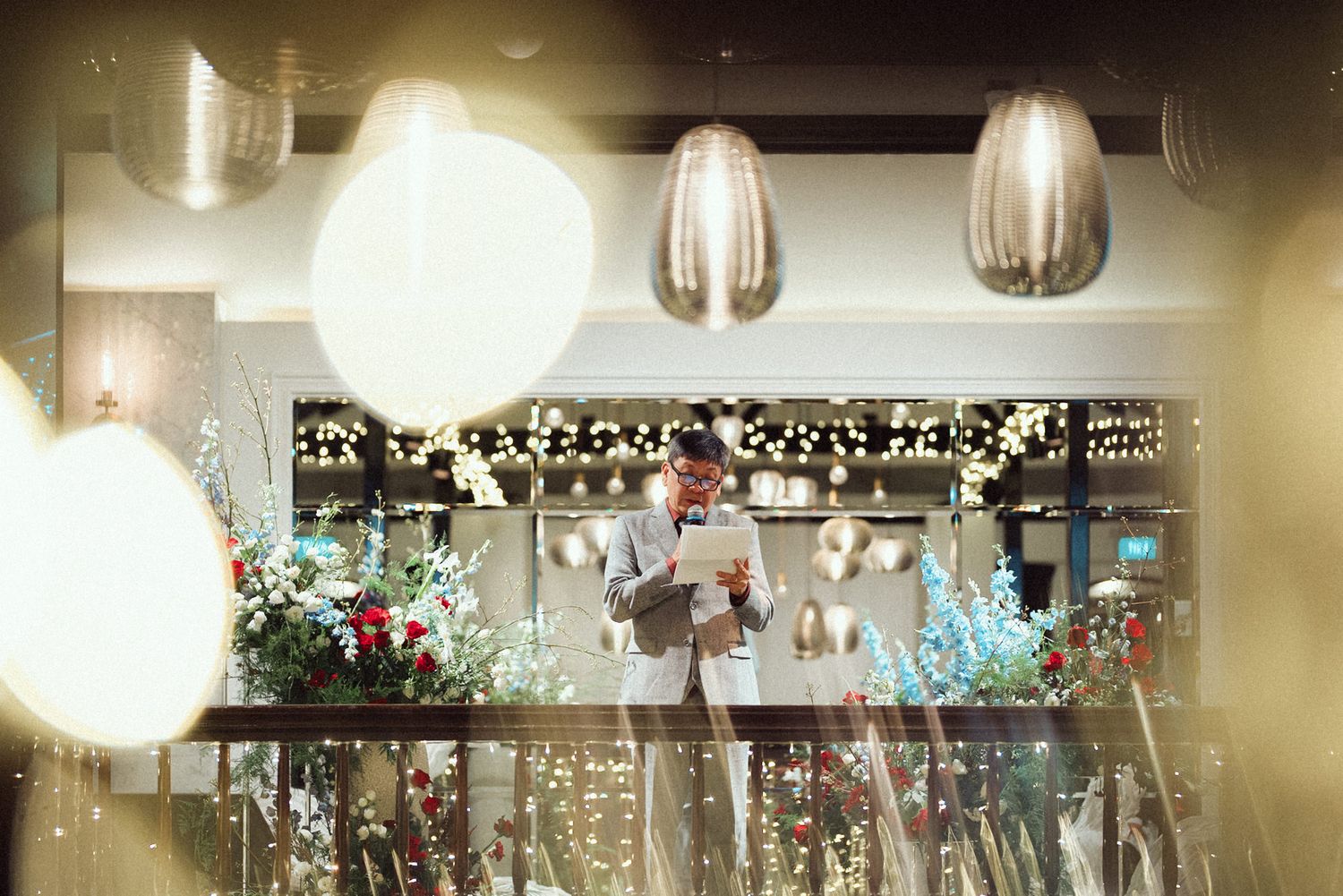 Wedding reception venue decorated with hanging lights and garlands creating a romantic ambiance in soft focus.