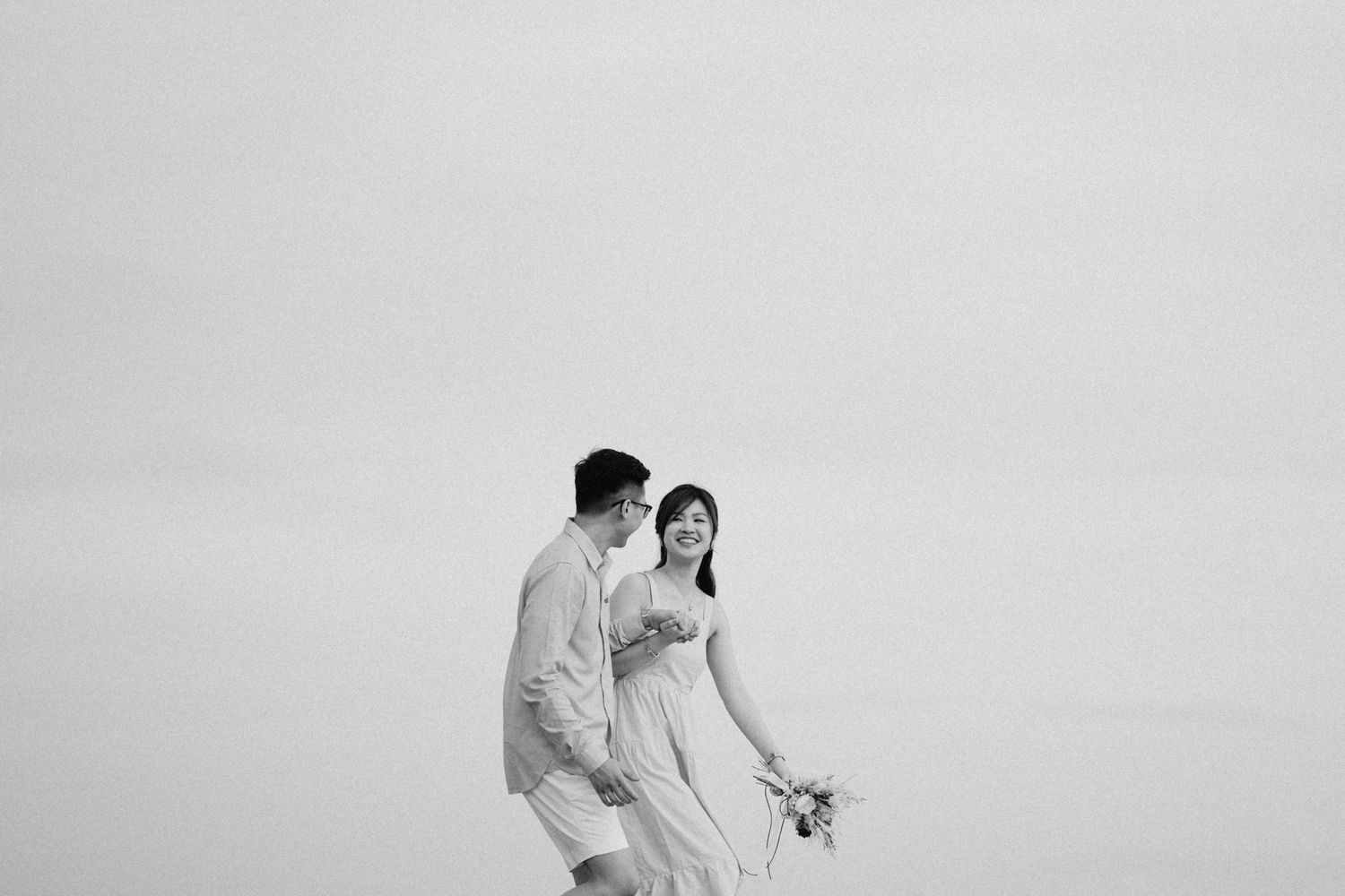 Black and white photo of a couple walking together in an elegant outdoor setting.