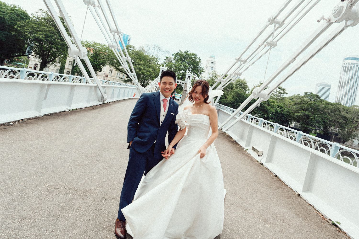 A couple in wedding attire shares romantic moments on a white bridge during their special day.
