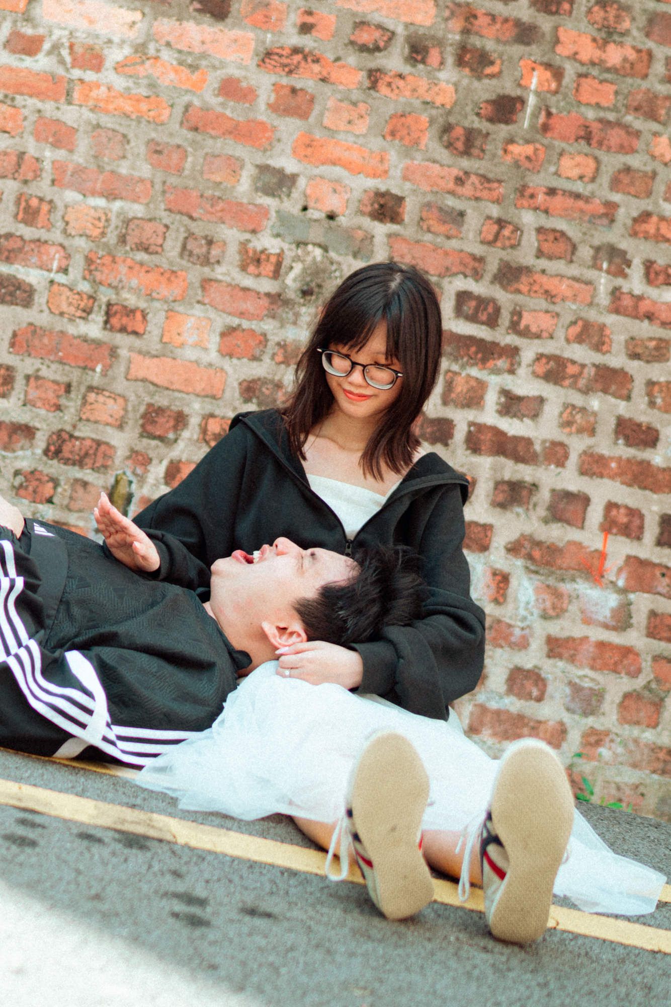 Three sequential photos show a playful moment against a brick wall background with casual clothing and sneakers.