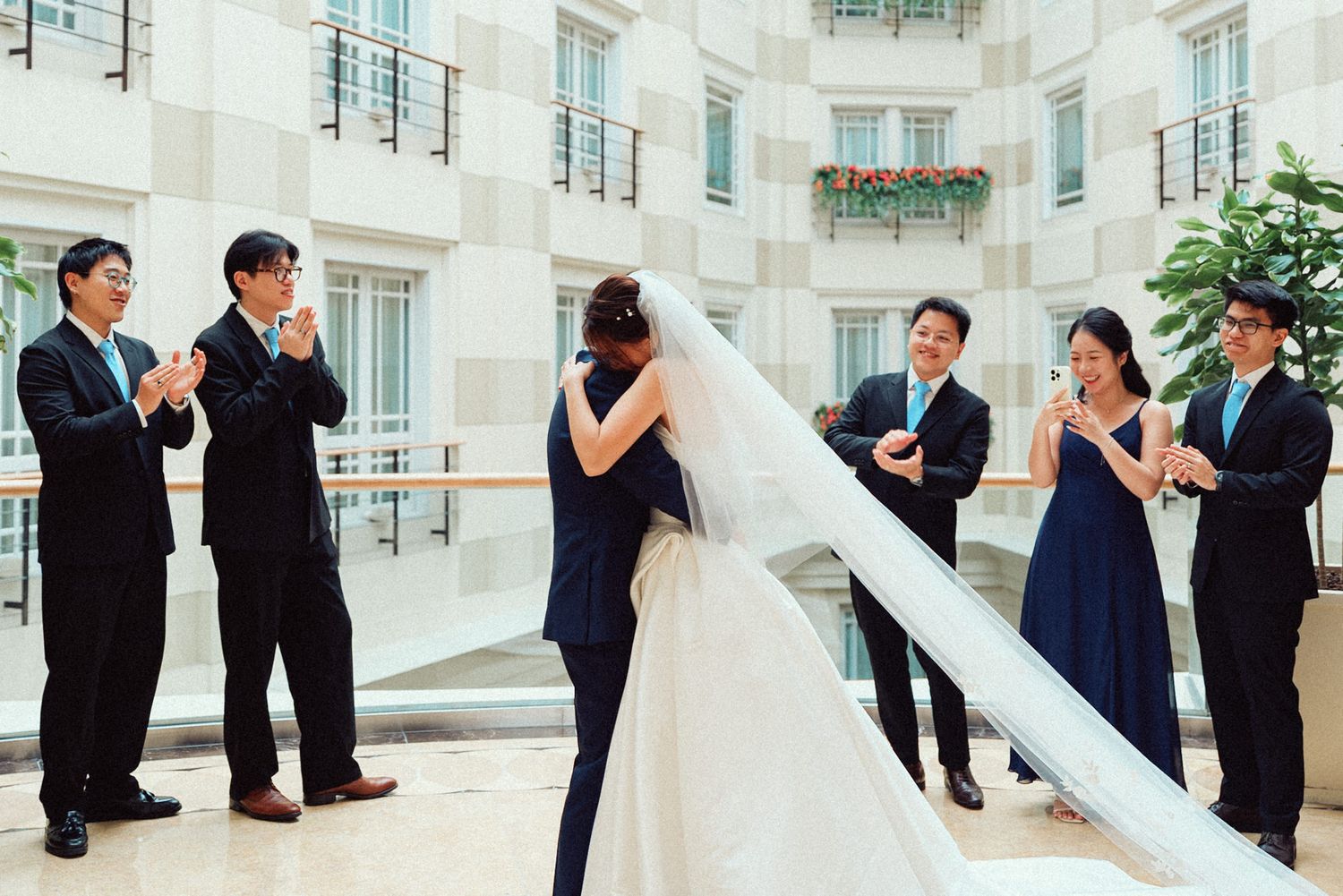 Wedding party stands in an elegant white corridor during formal photo session.