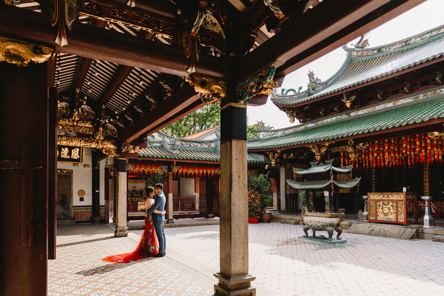 Traditional Asian temple architecture with ornate wooden beams and red lanterns hanging from the ceiling.