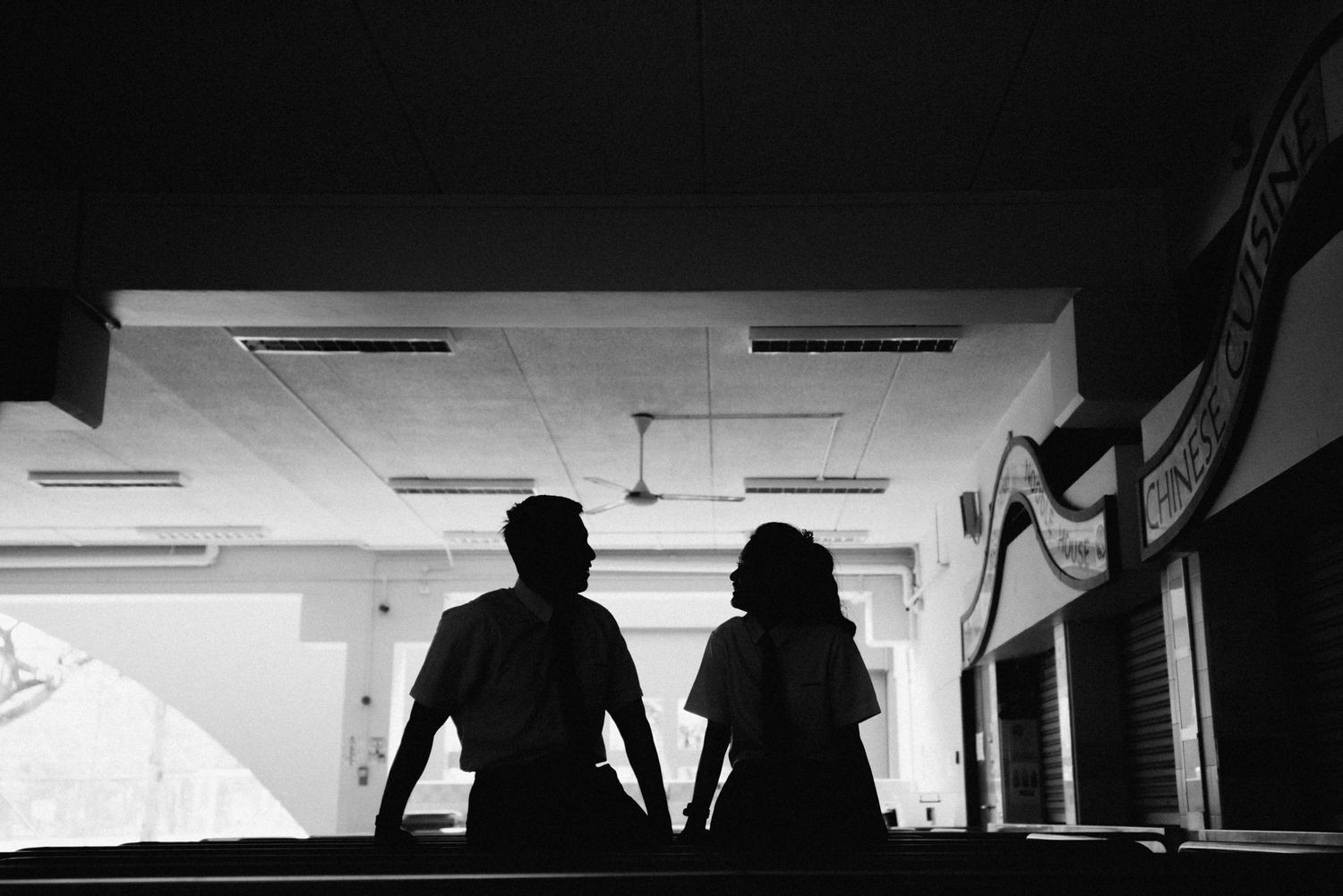 Silhouetted figures in a dimly lit indoor space creating dramatic contrast.