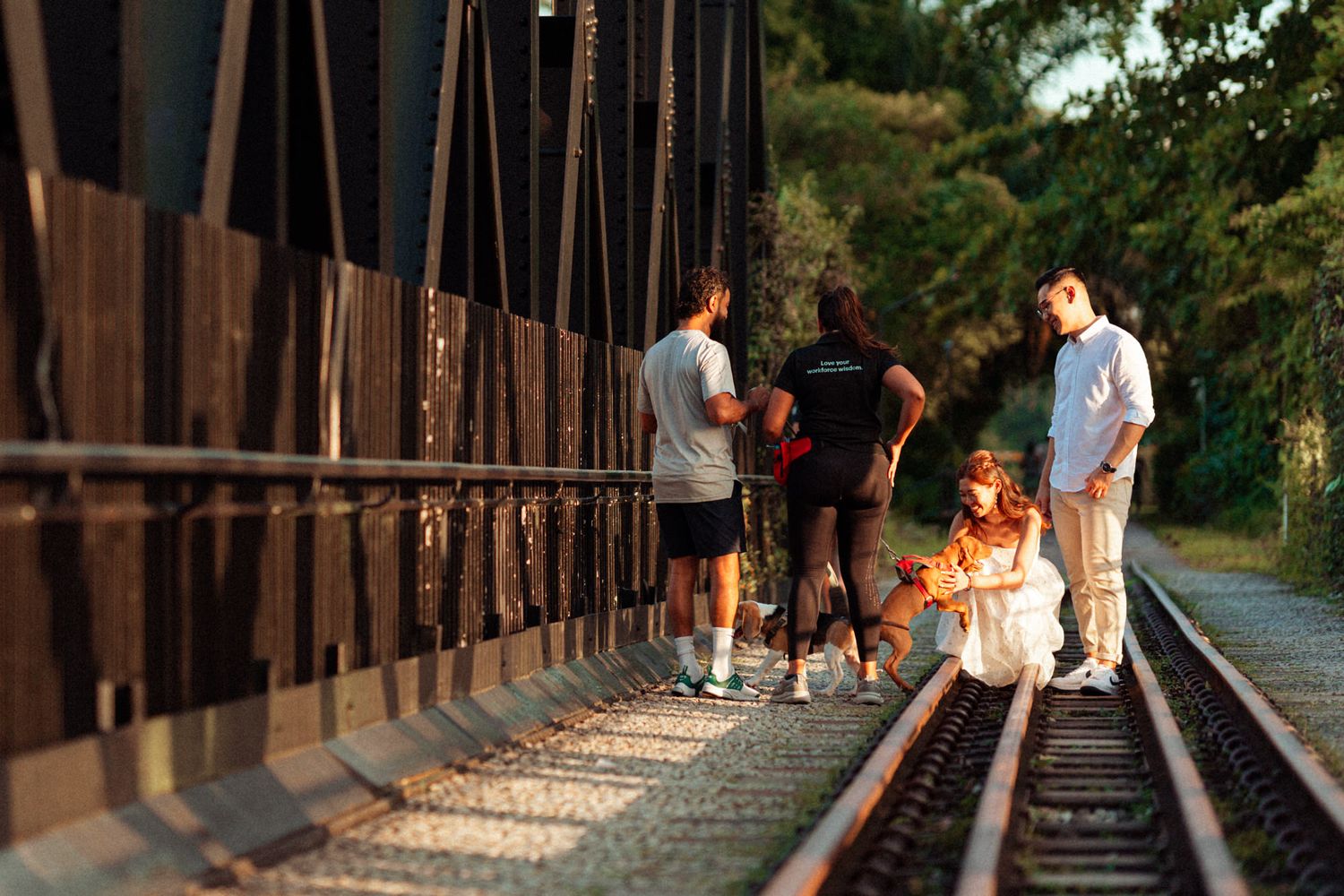 People walking along rustic railway tracks surrounded by nature.