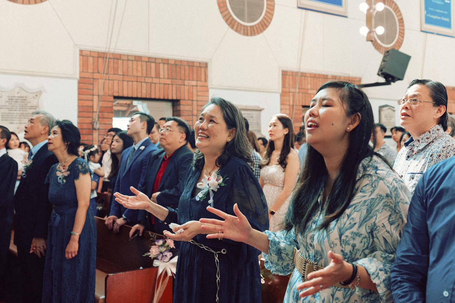 Wedding guests watching ceremony in church pews with expressions of joy.