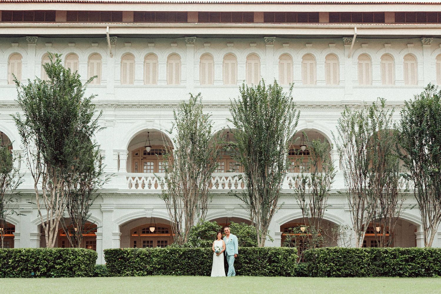 White Mediterranean-style colonnade with arched walkways and palm trees creates an elegant architectural backdrop.