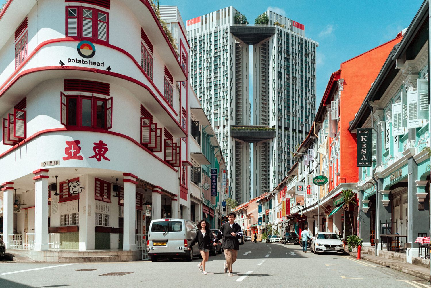 Panoramic view of a Singapore street with traditional shophouses and modern high-rise buildings in the background.