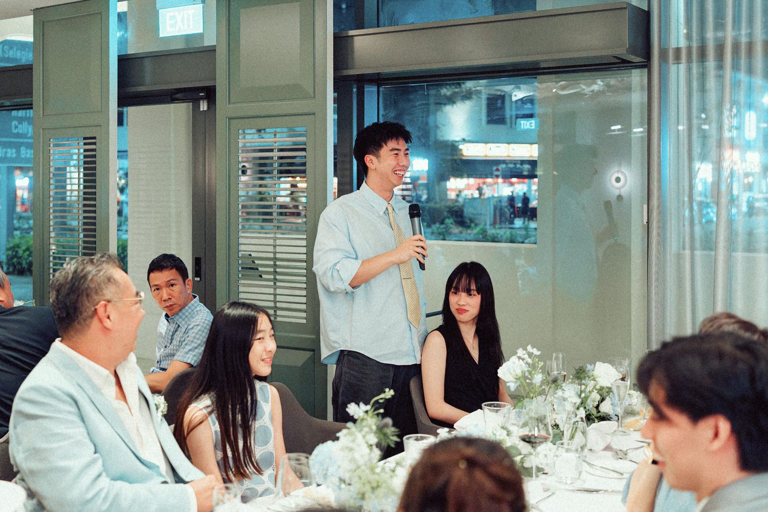Formal dinner gathering with multiple tables of guests in an upscale restaurant setting with modern decor.