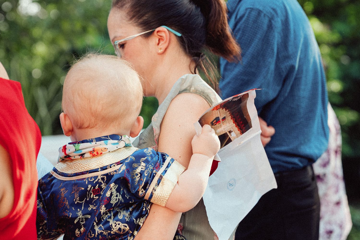 A couple shares a tender moment during an outdoor celebration with guests in the background.