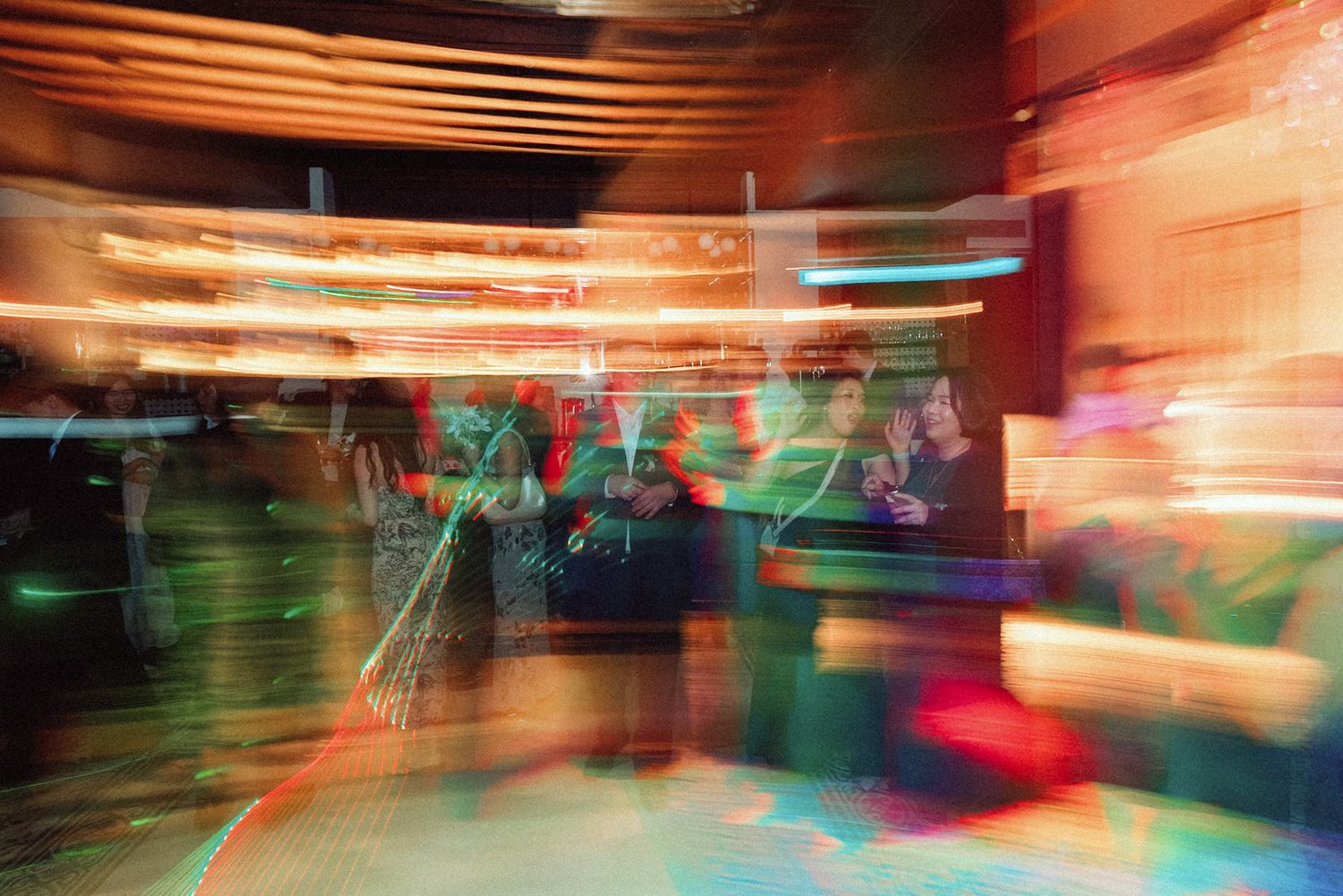Long exposure photograph of blurred lights and movement creating colorful light trails in an indoor space.